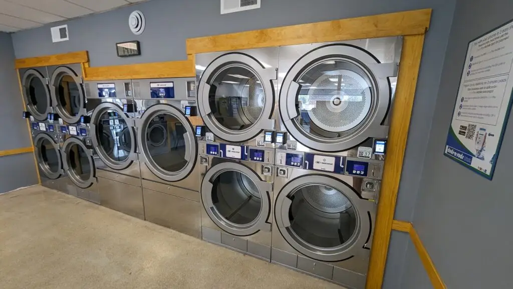 a group of washing machines in a room -  laundromat vs home washer